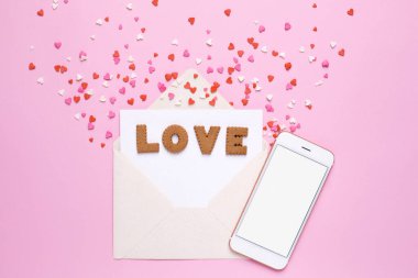 Zarflı aşk kurabiyeleri ve pembe arka planda kırmızı kalpler.