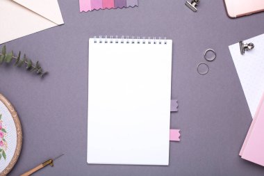 Gri arkaplan üzerine pembe kitabı olan beyaz not defteri