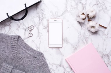 Kadın iş günü, cep telefonu ve pembe defterle mermer masa manzaralı.