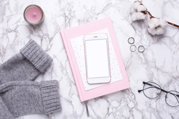 Kadın iş günü, cep telefonu ve pembe defterle mermer masa manzaralı.