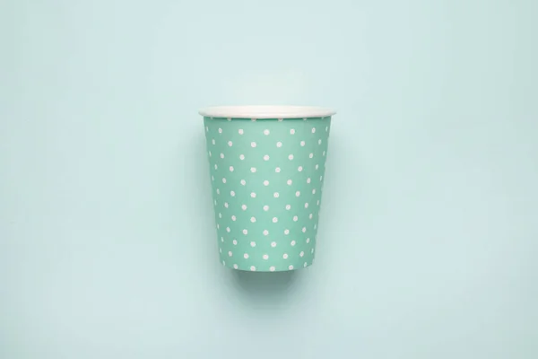 Paper cup with polka dot print green color on mint background. Eco friendly takeout cup for drink top view