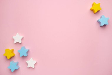 Çocukların eğitimsel oyunlarına en iyi bakış açısı, pembe kağıt üzerinde çok renkli çocukların oyuncaklarından çerçeve. Tahta mavi yıldızlar. Düz konum, metin için boşluk kopyala