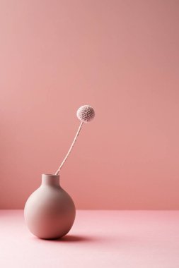 Tarafsız pembe arka planda gölgelerde kurumuş çiçekli şeffaf küçük vazo. Minimalist bileşim arkaplanı, kopyalama alanı