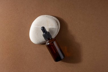 Kahverengi cam kozmetik ürünü şişesi ya da bej kahverengi kağıtta taş üstüne yağ. Sert gölgeli Natura Spa Güzellik Konsepti