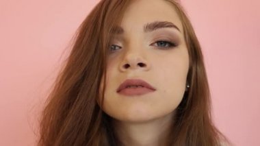 Pembe arka planda uzun saçlı ve mavi gözlü güzel bir genç kız. Kızlar Yüzü kameraya seksi görünüyor. Moda makyaj, çok uzun kamçılar yan görünümü