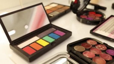 Önemli bir olaya hazırlanan kadının makyaj malzemeleri, kozmetik palet, ruj, beyaz masadaki fırçalar.