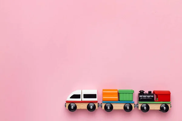 Тренировать детей игрушки, дошкольные игры детей. Локомотивы и вагоны, деревянные красочные блоки конструкции на розовом фоне — стоковое фото