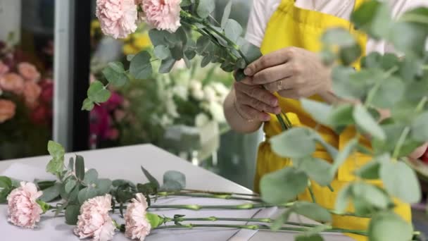 Vista laterale di un fioraio in grembiule giallo che lega un mazzo di fiori tenendoli in mano. Colpo di rallentamento — Video Stock