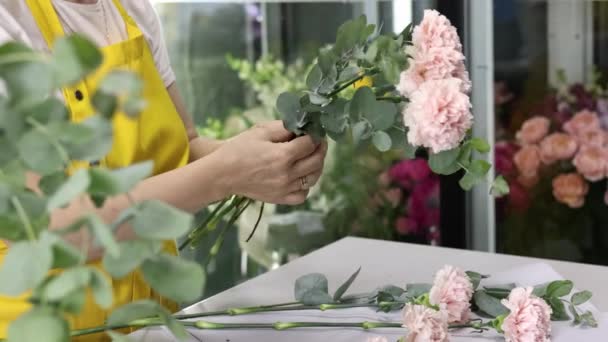 Seitenansicht einer Verkäuferin in gelber Schürze, die einen Blumenstrauß in Händen hält. Zeitlupenschuss — Stockvideo
