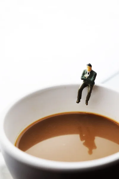 Miniatűr üzleti ember ül a csésze kávé — Stock Fotó