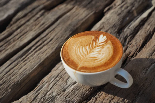 Cangkir kopi latte art pada latar belakang kayu dalam warna vintage — Stok Foto