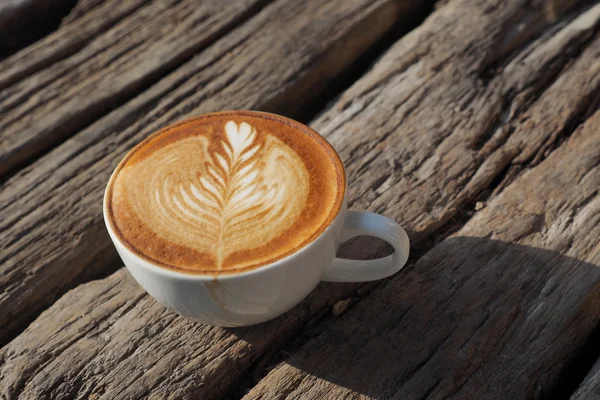 Kopje koffie latte kunst op de houten achtergrond in vintage kleur — Stockfoto