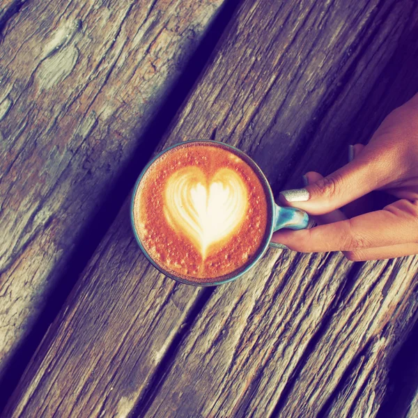 Hand and cup of coffee latte art on the wood background vintage — Stock Photo, Image