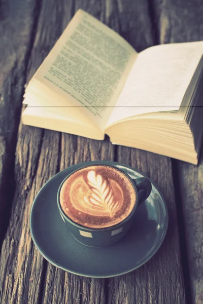 Cup of coffee latte art on the wood desk and book in vintage col — Stock Photo, Image