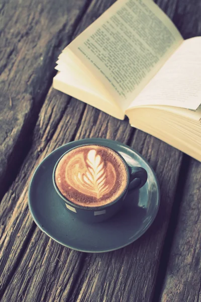 Kopp kaffe latte art på trä skrivbord och bok i vintage col — Stockfoto