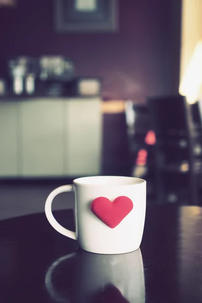 Vintage kleurtoon van een kop van koffie met rood hart op de tabel — Stockfoto