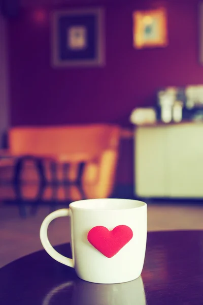 Vintage kleurtoon van een kop van koffie met rood hart op de tabel — Stockfoto
