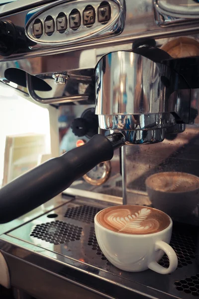 Kop kaffe latte kunst på træ baggrund i vintage farve - Stock-foto