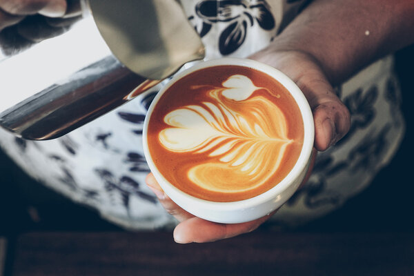 чашка кофе латте искусства на деревянном фоне в винтажном цвете
 