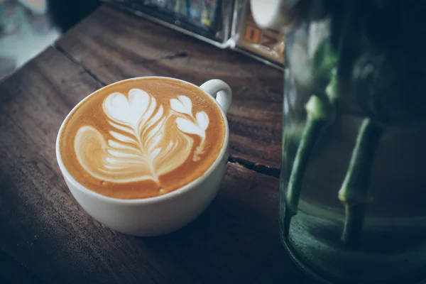 Cangkir kopi latte art pada latar belakang kayu dalam warna vintage — Stok Foto