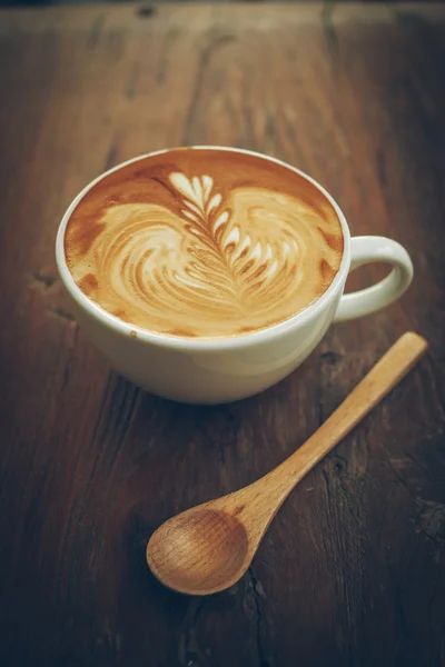 Šálek kávy latte art na dřevěný stůl — Stock fotografie