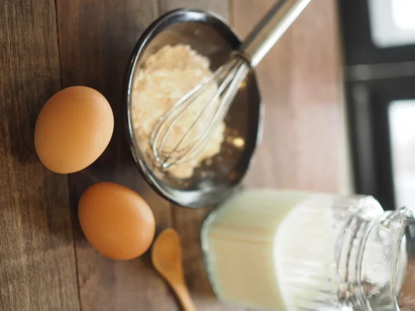 Baking cake ingredients. Bowl, flour, eggs on the wood desk