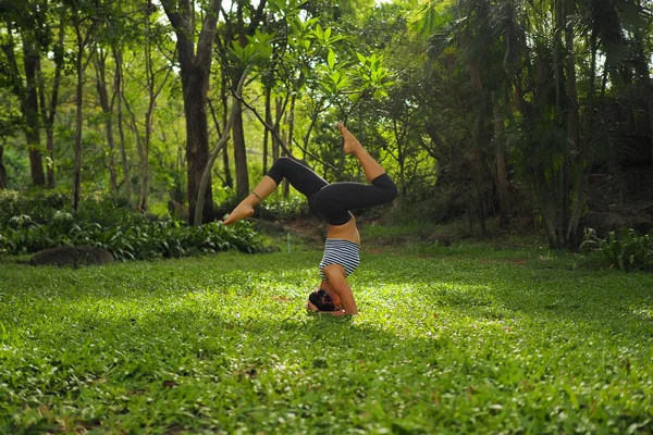 Νεαρή γυναίκα να κάνει ασκήσεις γιόγκα στο πάρκο κήπων — Φωτογραφία Αρχείου