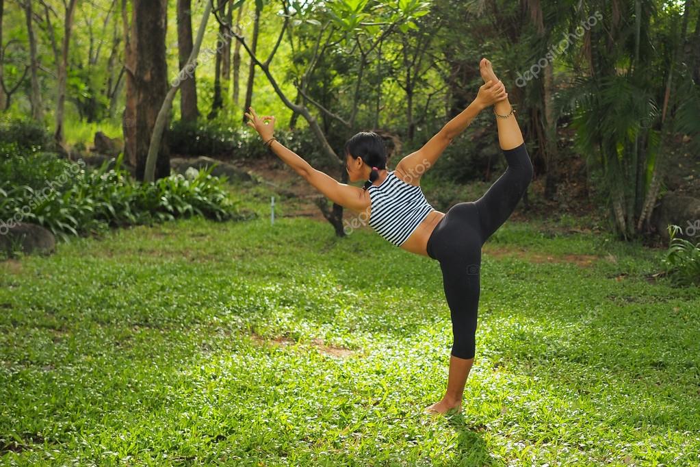 Junge Frau macht YogaÜbungen im Gartenpark