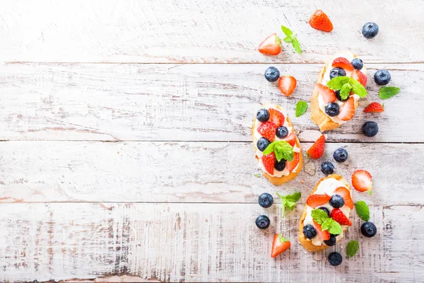 Crostini met gegrilde stokbrood, roomkaas en bessen — Stockfoto