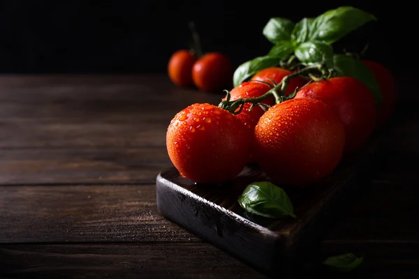 Ramo di pomodori naturali maturi e foglie di basilico — Foto Stock