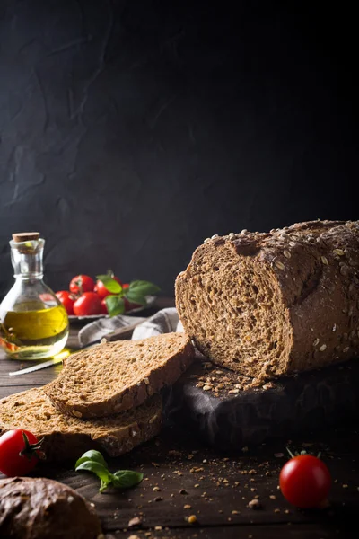 Pão, azeite, tomate e manjericão sobre tábua de corte de madeira — Fotografia de Stock