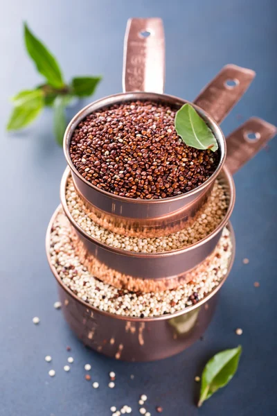 Pila di tre misurini in rame con quinoa cruda mista — Foto Stock