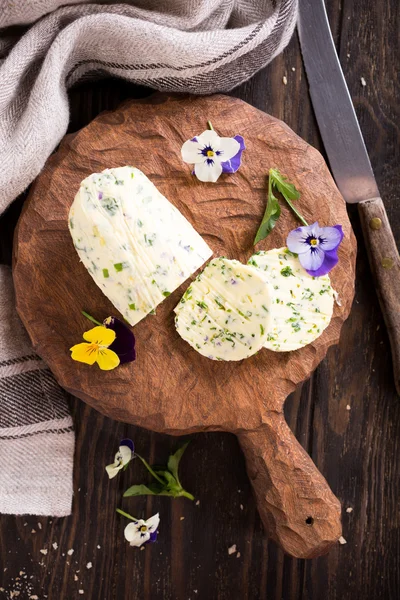 Manteiga de ervas com flores comestíveis em tábua de corte de madeira — Fotografia de Stock