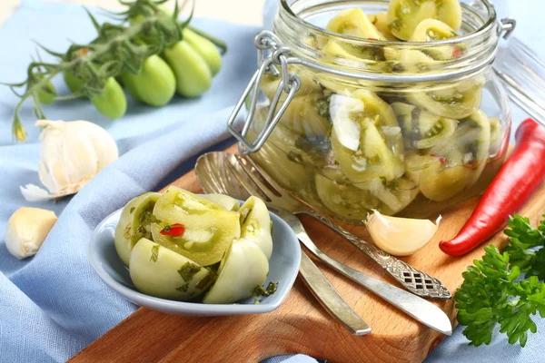 Tomates verdes em conserva em tigela azul e em frasco de vidro — Fotografia de Stock