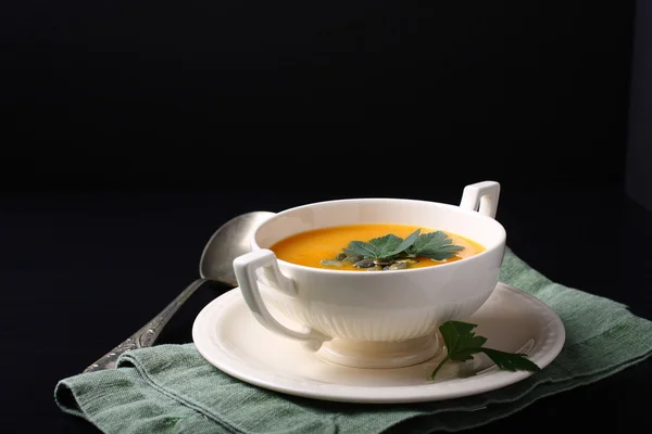 Pumpkin soup in white plate on black background — Stock Photo, Image