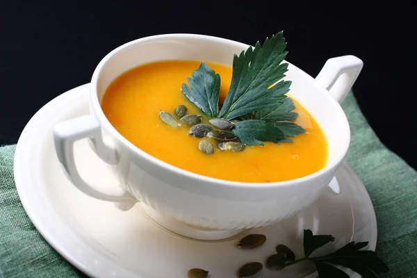 Pumpkin soup in white plate on black background — Stock Photo, Image