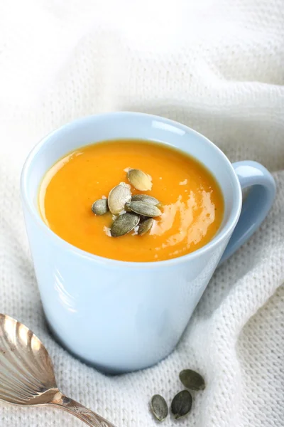 Blue cup of pumpkin soup on the knitted woolen fabric — Stock Photo, Image