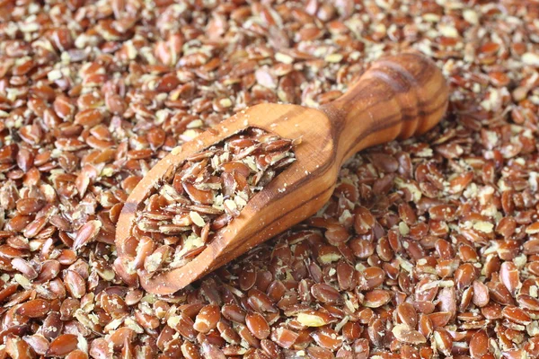Broken flax seeds in wooden scoops — Stock Photo, Image