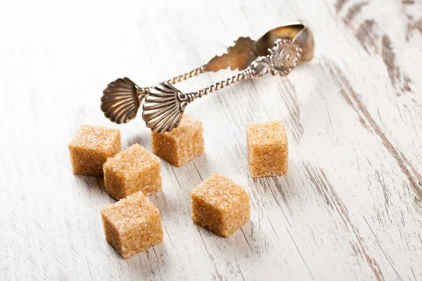 Cubos de açúcar mascavo e pinças de metal açucarado — Fotografia de Stock