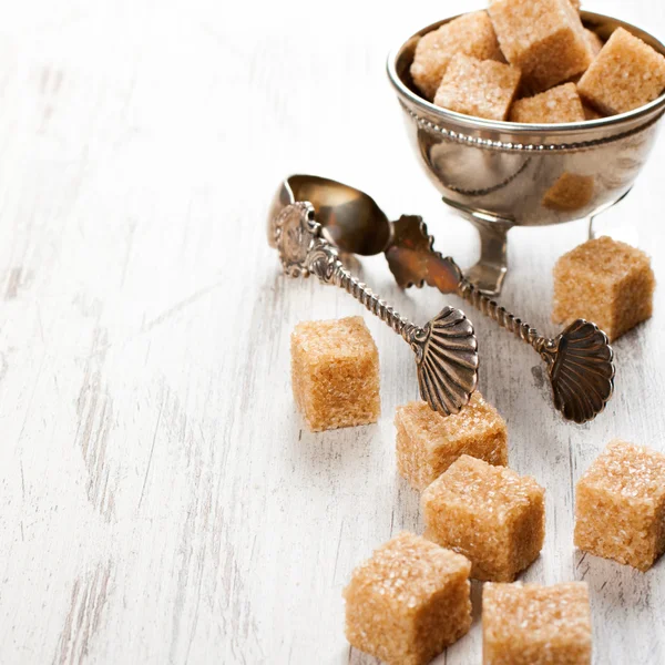 Brown sugar cubes and metal sugat tongs — Stock Photo, Image