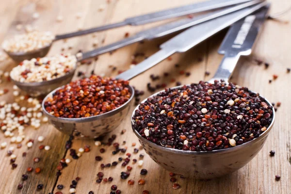 Mistura de grãos de quinoa em colheres de medição de metal — Fotografia de Stock