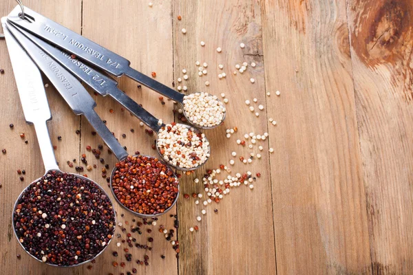 Mistura de grãos de quinoa em colheres de medição de metal — Fotografia de Stock