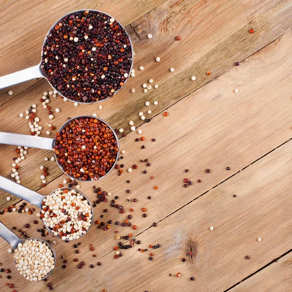 Mix of quinoa grain in metal measuring spoons — Stock Photo, Image