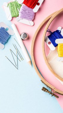 Renkli iplikler, iğneler ve halkalar da dahil olmak üzere nakış malzemeleri pastel bir arka planda sanatsal olarak düzenlenmiştir. Temel el işleri sergilenmektedir. Kopya alanı olan hikayeler.