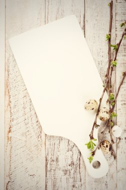 Bıldırcın yumurtası, yeşil dallar ve beyaz kesme tahtası