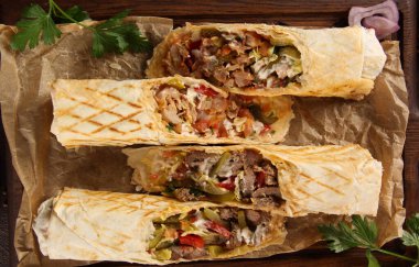 Et ve sebzeli Shawarma. Kuzu eti, tavuk, turşu, soğan, hardal ve sosla ahşap bir tahtada. Arkaplan resmi, üst görünüm