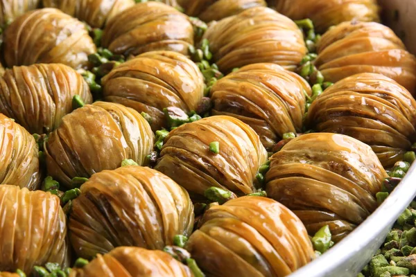 Oriental sweets. Pahlava with nuts, pistachio in a large dish on a black table. Turkish dessert. Background image, copy space, horizontal