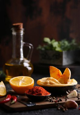 Atıştırmalıklar Kasede mayonez soslu Rus patatesleri, baharatlar, kırmızı biber, limon, sarımsak ve kırmızı biber. Ahşap bir arka planda zeytinyağı ve bitkiler. Arkaplan resmi, kopyalama alanı, dikey