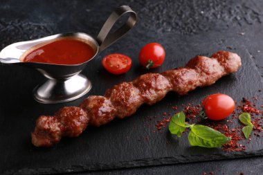 Şiş kebap, barbekü. Siyah bir masada et kebabı yemek. Taze sebzeli, domatesli, baharatlı, biberiyeli ve soslu kızarmış et. Arkaplan resmi, alanı kopyala