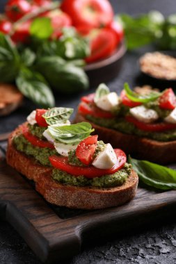 İtalyan mutfağı. Taşralı. Pesto sosu, taze domates, mozzarella ve fesleğen ile ahşap bir tahtada siyah bir masa. Arkaplan resmi, alanı kopyala. 